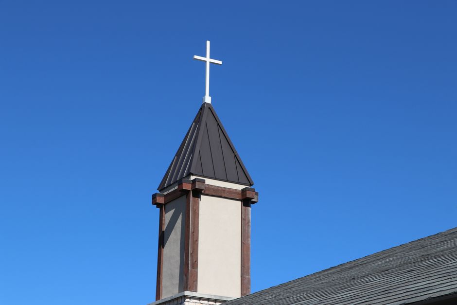 A serene church tower with a cross under a vibrant blue sky in Allen, Texas.