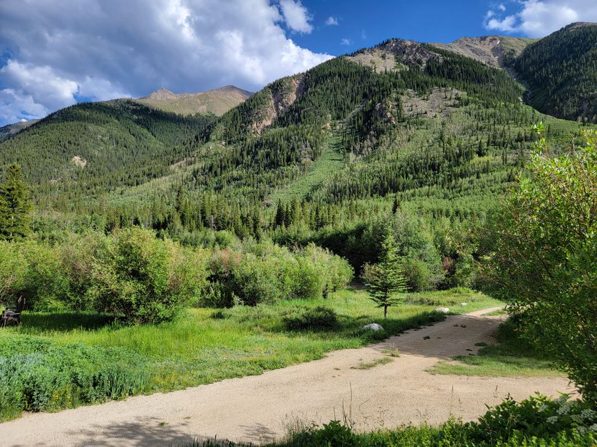 Lush green landscape with mountains under a bright blue sky in Colorado.