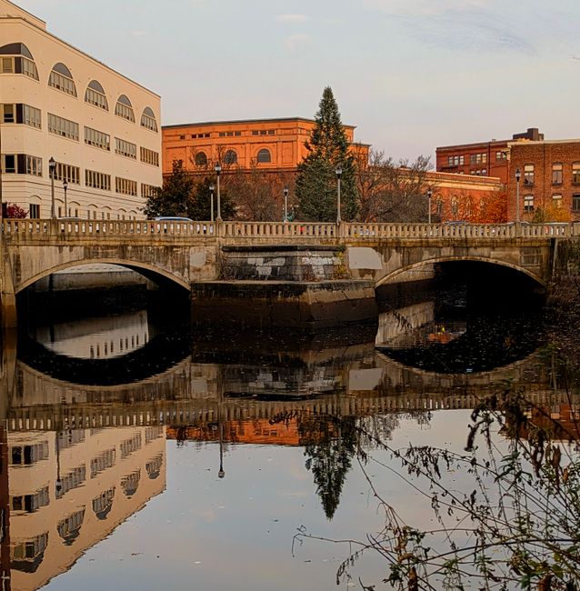 Charming bridge in downtown reflecting in calm water during a serene daytime setting.