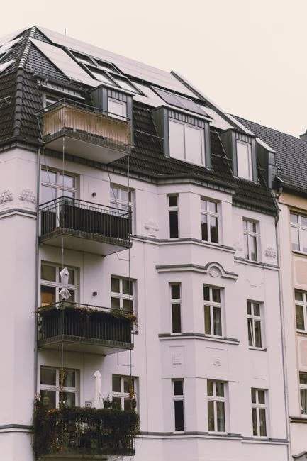Charming urban exterior of a European apartment building with balconies and solar panels.