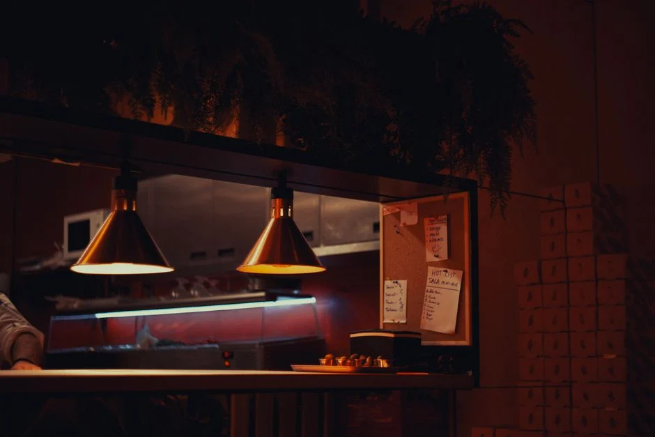 Warmly lit urban kitchen interior with counter, lamps, and cozy atmosphere at night.