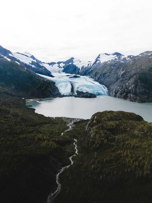 Breathtaking aerial shot of snowcapped mountains and Portage Glacier in Alaska's rugged landscape.
