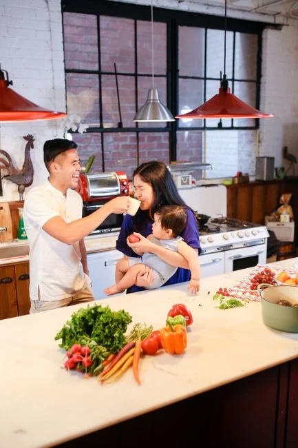 Asian family enjoying food preparation with fresh vegetables in a cozy kitchen setting.