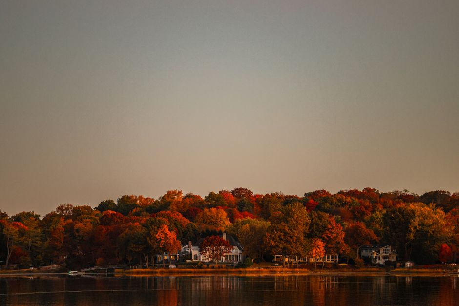 Serene autumn landscape with vibrant foliage reflecting in tranquil waters during sunrise in Stamford, Connecticut.