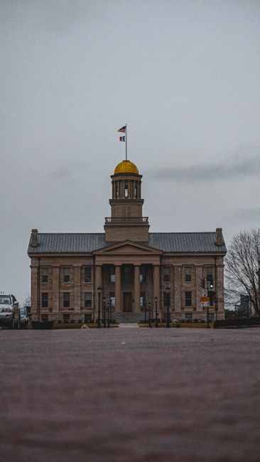 Front view of Old Capitol Museum in Iowa City with American flag atop during twilight.