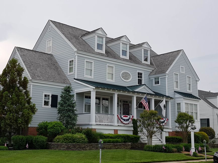 Elegant colonial-style house in Cape May, NJ with manicured lawn and American flags.