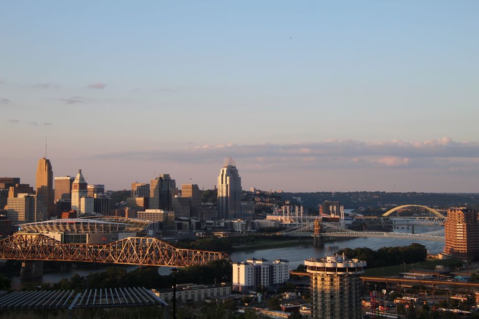 Panoramic view of Cincinnati skyline with bridges at dusk.