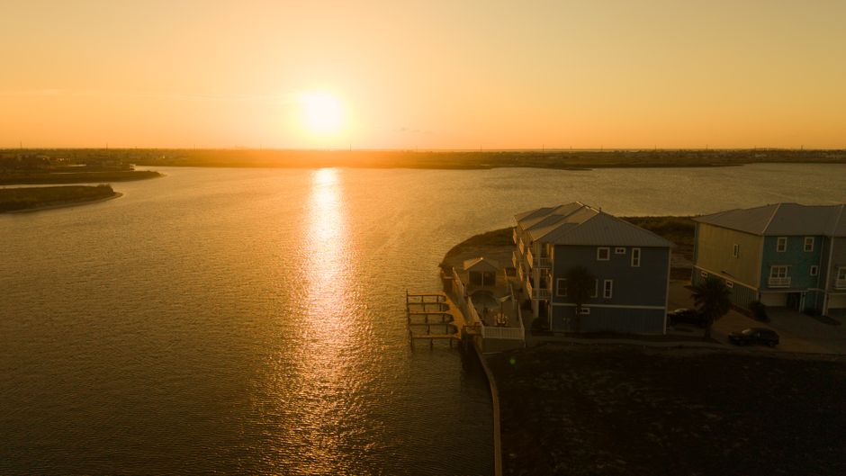 Tranquil sunset over Corpus Christi with waterfront homes and golden reflections.