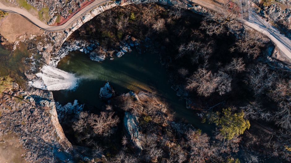 Stunning aerial view of a waterfall surrounded by rocky landscape and trees in Gadsden, Alabama.