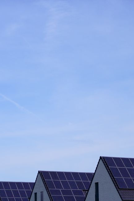 Modern residential houses with solar panels under clear blue sky, promoting renewable energy.