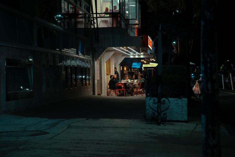 A cozy street cafe with people dining outdoors at nighttime, creating an inviting atmosphere.