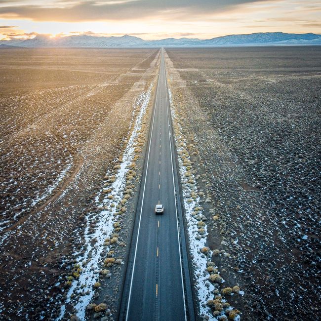 Aerial view of a long straight road cutting through the desert in Fallon, Nevada at sunset.