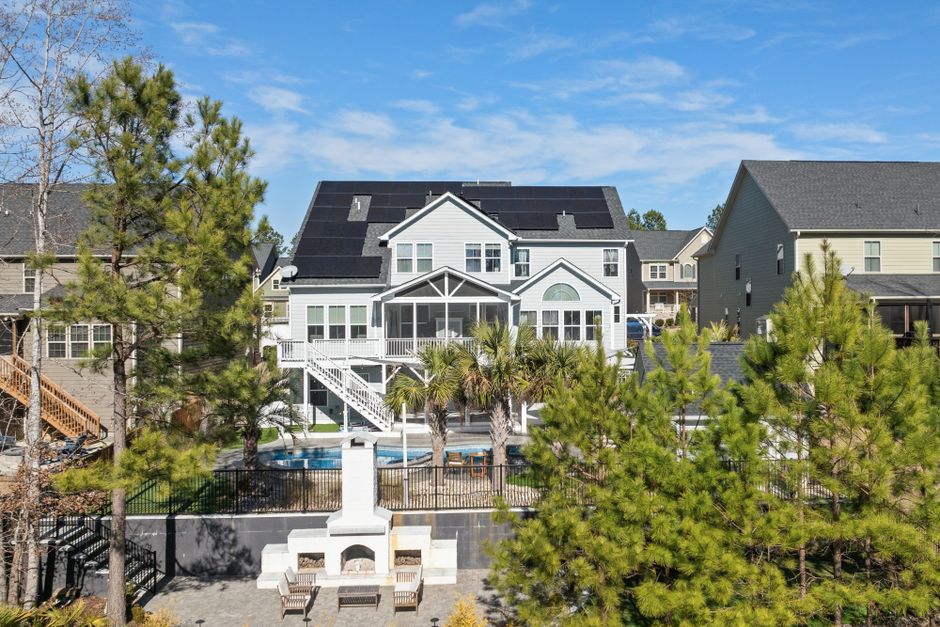 A stylish suburban home featuring solar panels and outdoor amenities under a clear blue sky.