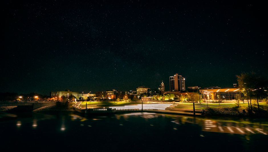 Captivating night view of Fort Wayne skyline with illuminated city lights and clear starry sky.