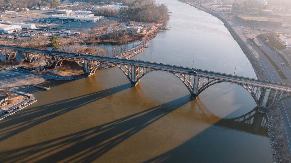 Stunning aerial shot of a bridge crossing over a calm river in Gadsden, Alabama during sunset.
