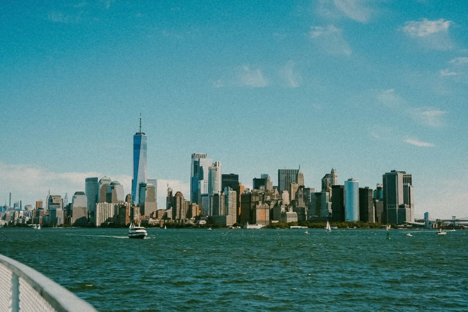 A breathtaking view of New York City's skyline from a river with boats and skyscrapers under a clear blue sky.