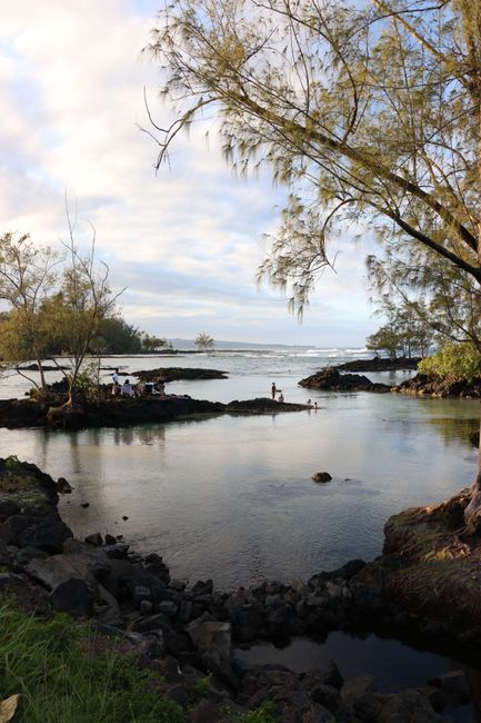 Tranquil beach scene in Hawaii showcasing tide pools and lush greenery under a setting sun.