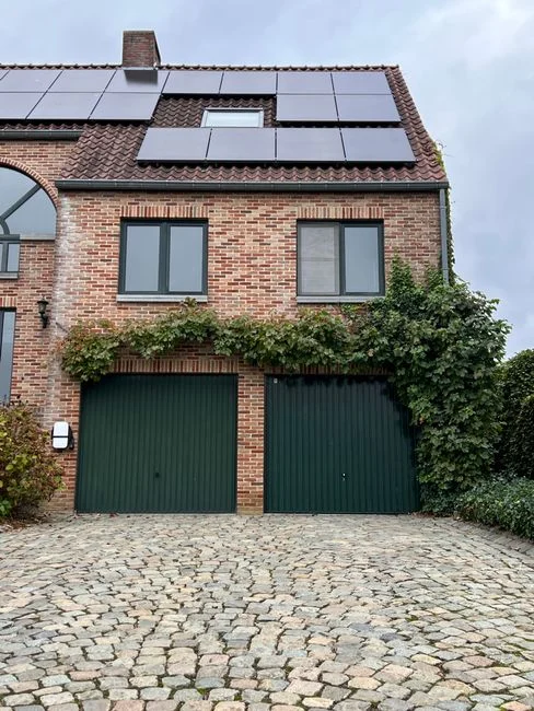 Charming brick house with solar panels and ivy-covered garage. Eco-friendly architecture.