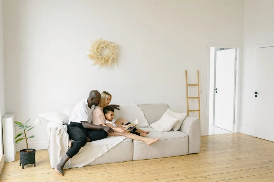 A loving family sharing quality reading time on a cozy couch in a bright, minimalist home.