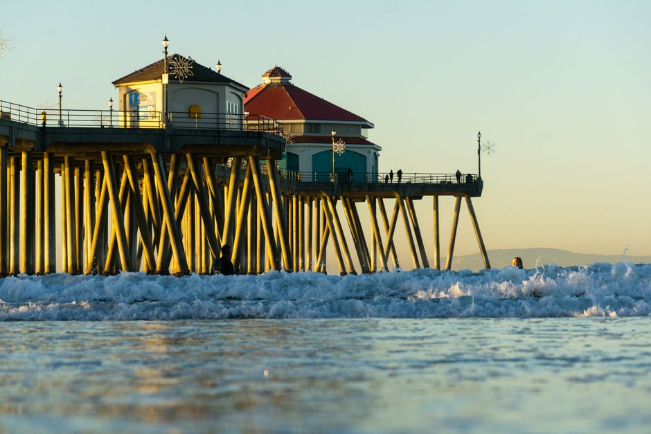 Coastal view of Huntington Beach Pier and ocean waves during a beautiful sunset in California.