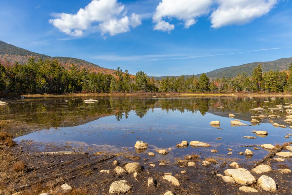 Serene autumn landscape of a reflective lake surrounded by trees in Franconia, New Hampshire.
