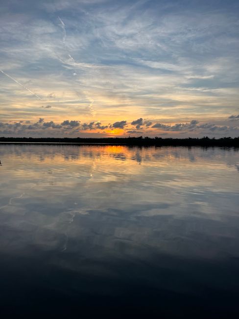 Tranquil sunset with reflective waters and a colorful sky, capturing a peaceful coastal scene.