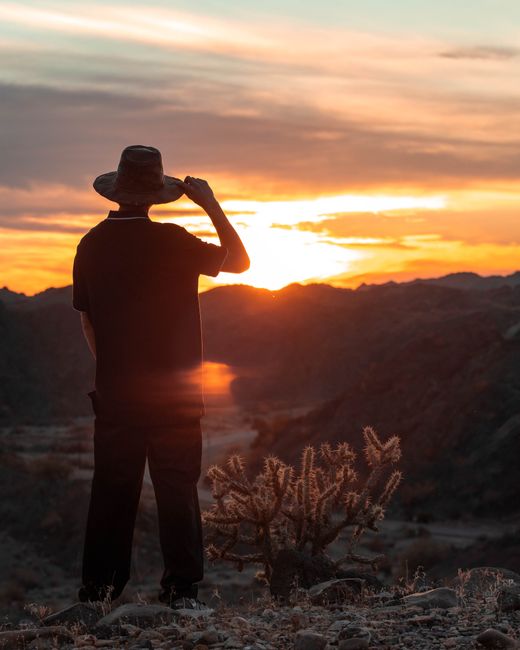 A man in silhouette enjoys a serene sunrise over the mountains in Lake Havasu City, Arizona.