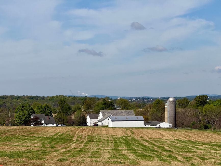 A scenic rural farm landscape with silos and barns in Pennsylvania under a blue sky.