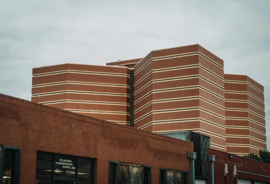 A perspective view of modern brick buildings with horizontal patterns under a cloudy sky.