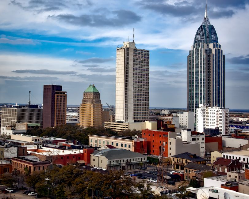 Vibrant urban skyline of Mobile, Alabama featuring iconic skyscrapers under a blue sky.
