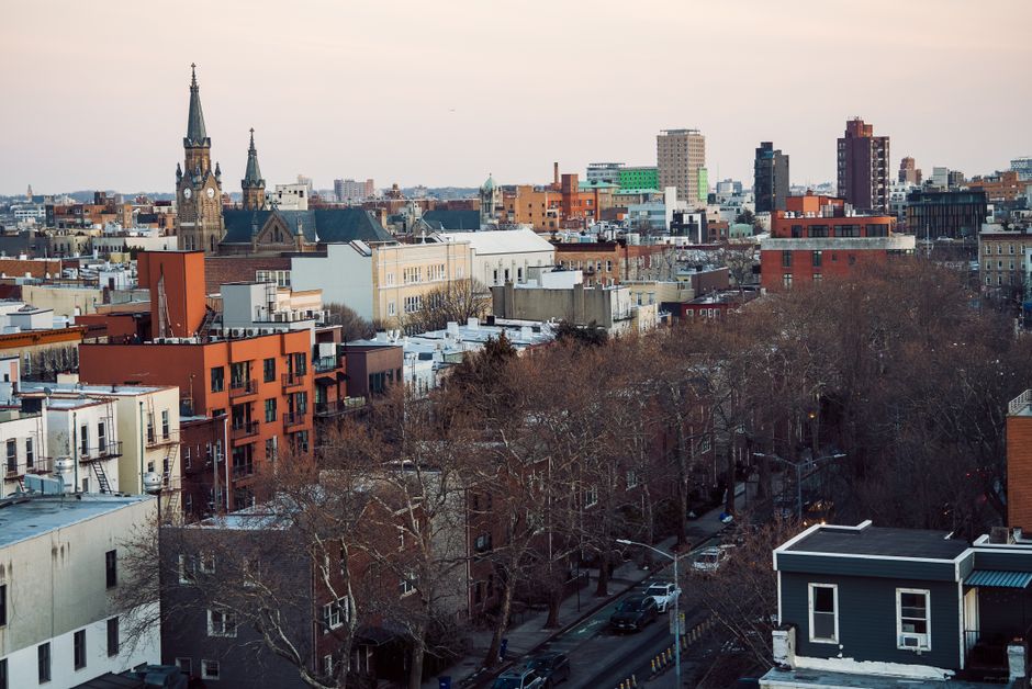 Aerial view of Brooklyn's cityscape featuring church spires and urban architecture at dusk.