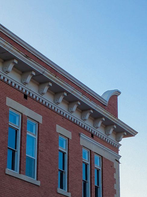 A detailed view of historic brick building architecture with ornate cornices and multiple windows.