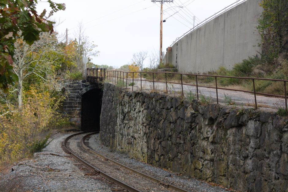 Scenic view of railroad tracks leading into a stone tunnel surrounded by fall foliage in Norwich, Connecticut.