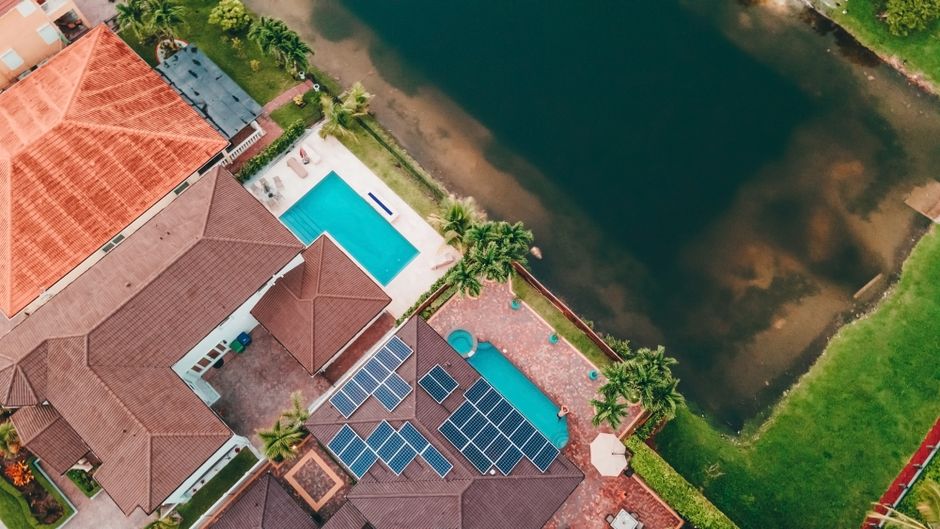 Top-down view of a Miami home with solar panels and pool near a lake.