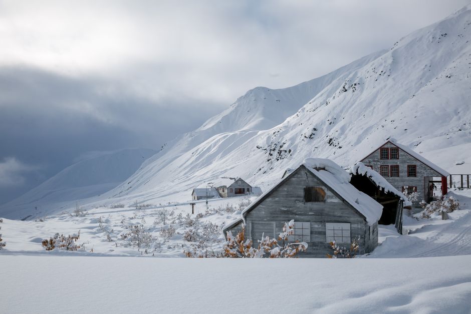 Serene winter landscape featuring snow-covered mountains and rustic houses in Palmer, Alaska.