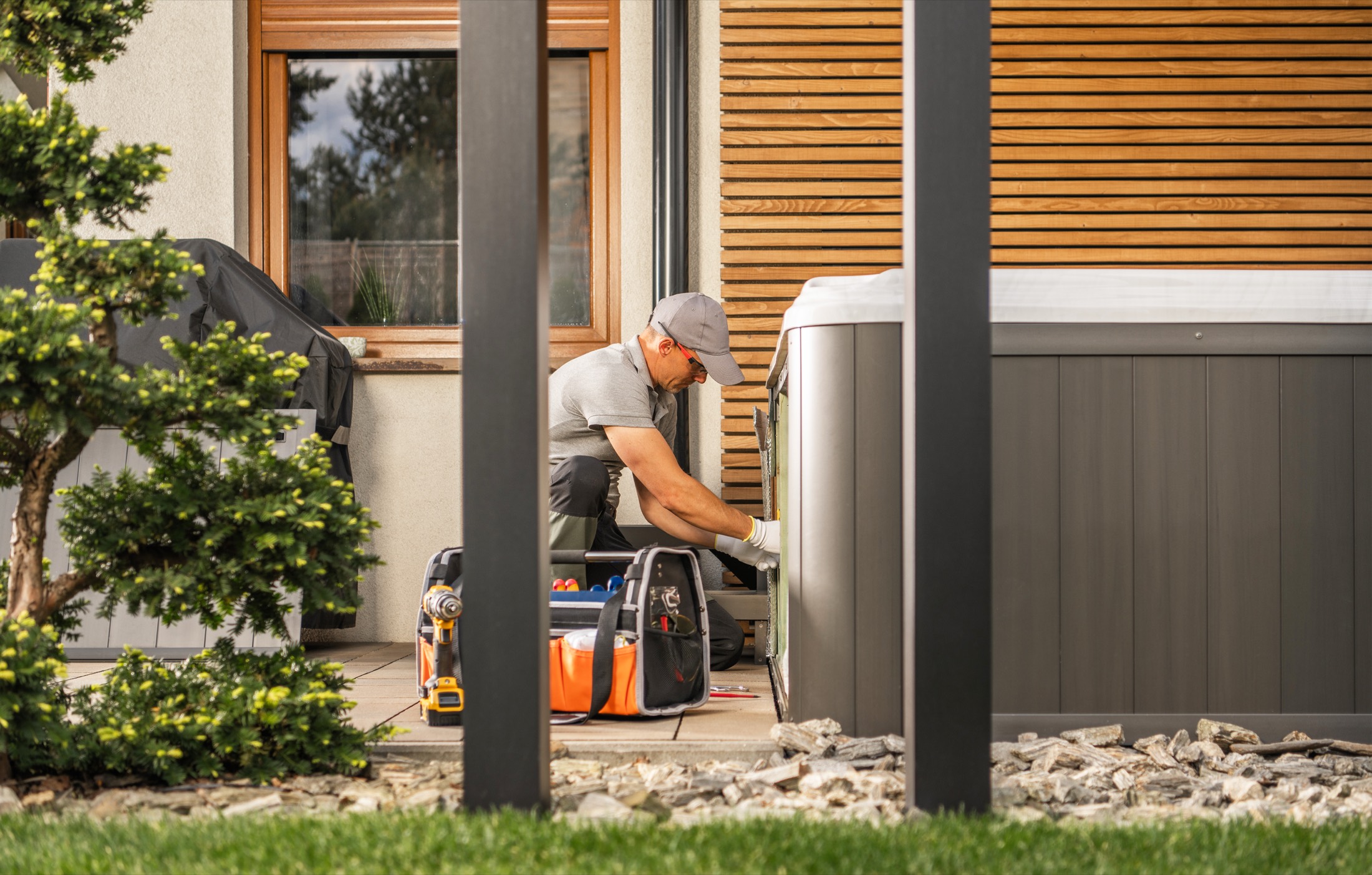 Technician working on outdoor equipment beside a home