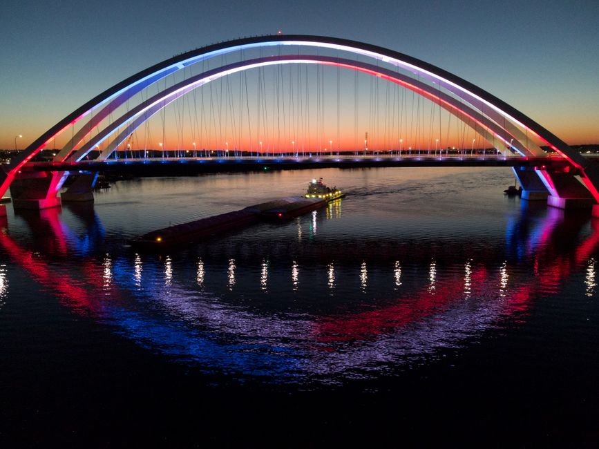 Colorfully lit I-74 bridge spans the river at sunset in Davenport, Iowa.