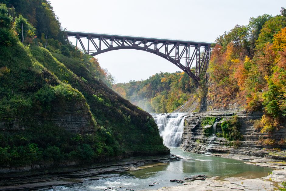 Magnificent bridge over cascading waterfall and lush autumn landscape in Letchworth State Park, Castile, NY.
