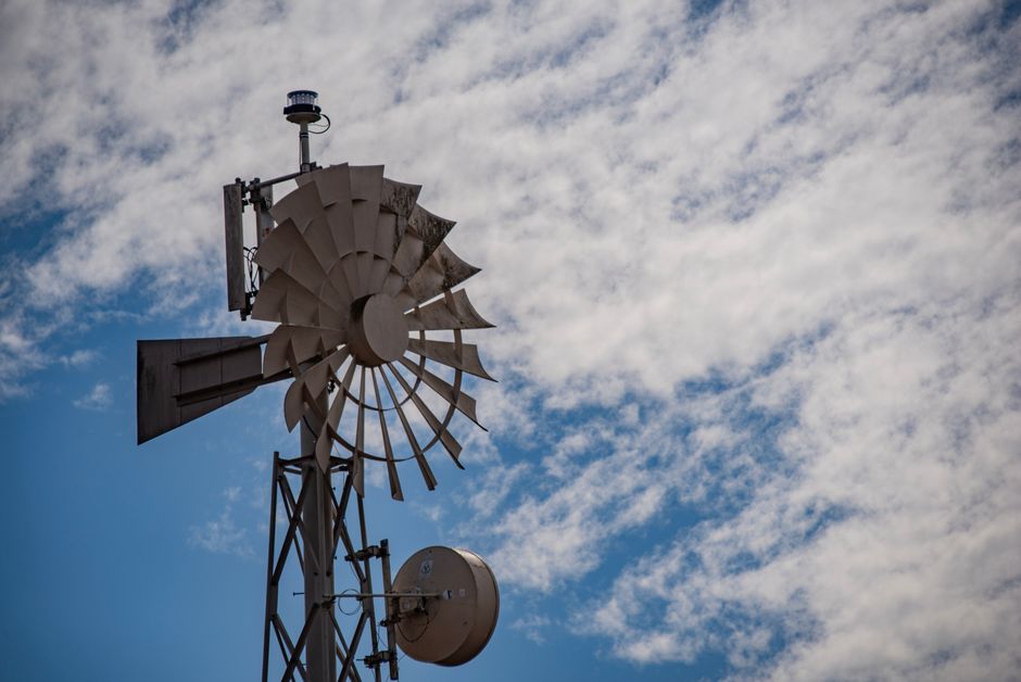 A detailed shot of a vintage windmill under a bright blue sky in Salinas, California.