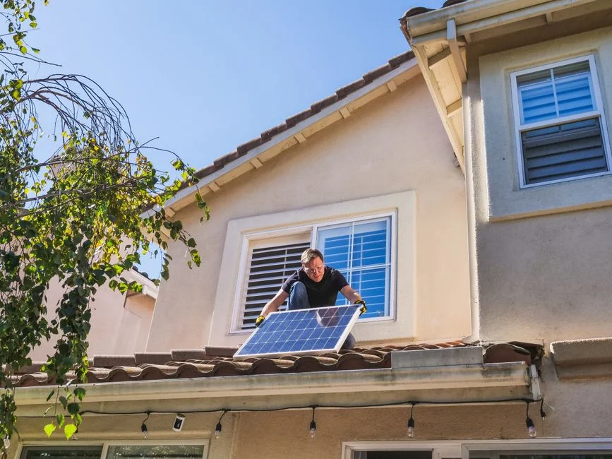 Solar technician installing photovoltaic panels on a sunny rooftop.