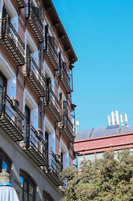 Elegant European apartment building in urban setting with solar panels and clear blue sky.