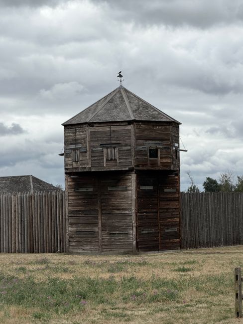 Old wooden fort tower with weathered texture under a cloudy sky, creating a moody atmosphere.