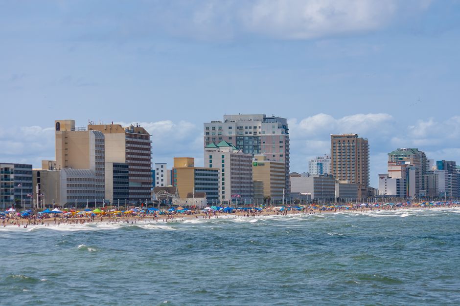 Lively scene of Virginia Beach boardwalk with bustling crowds enjoying a sunny day by the ocean.