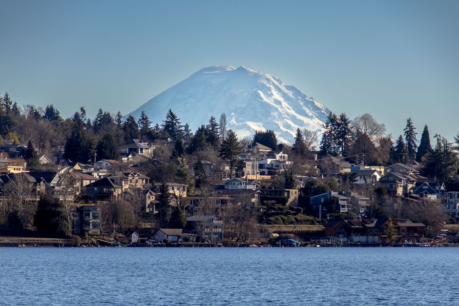 Scenic view of Mount Rainier with residential suburb along the water on a clear day.