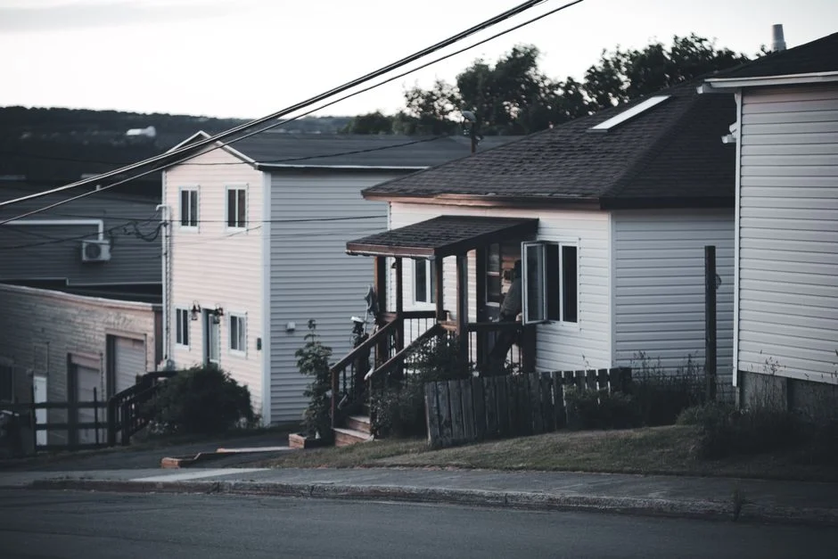 Peaceful residential street with houses and power lines during dusk, creating a quiet suburban atmosphere.