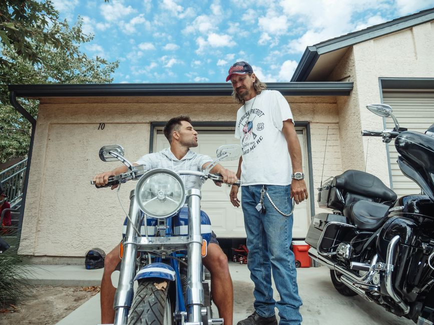 Father and son sharing a moment with motorcycles in a garage driveway.