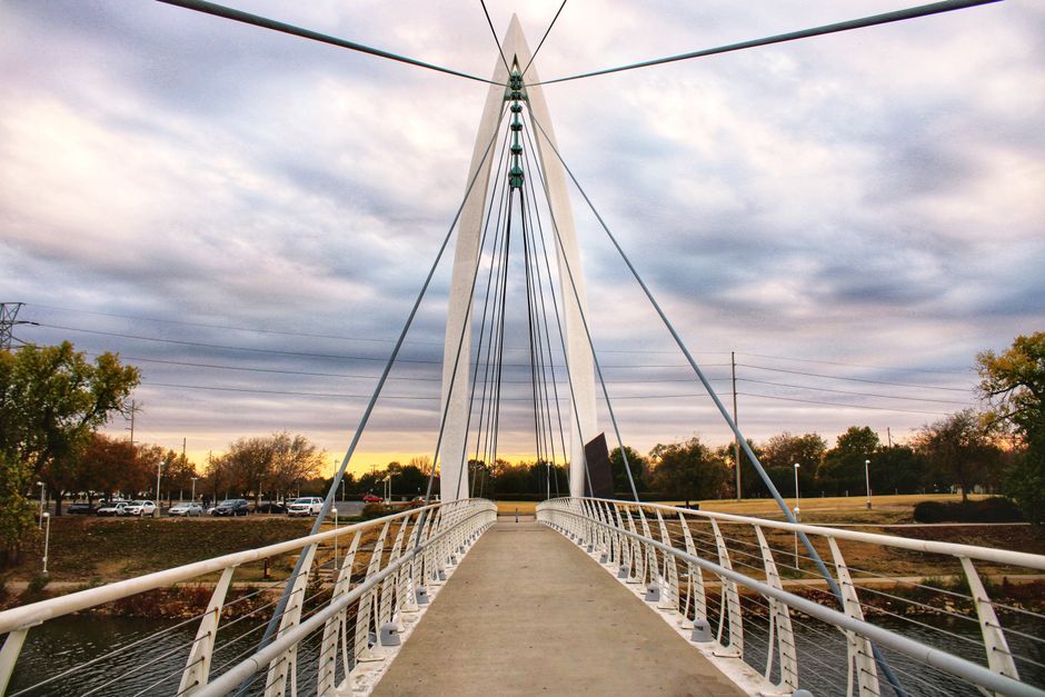 A stunning view of a suspension bridge in Wichita, KS, during sunset, showcasing architectural beauty.