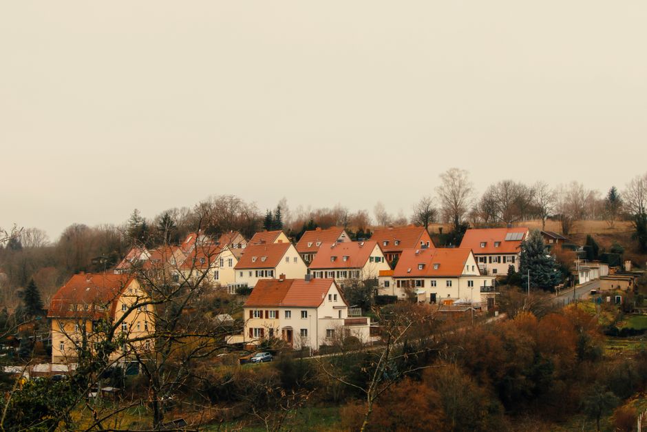 Charming village houses nestled in an autumn landscape with warm orange roofs and bare trees.